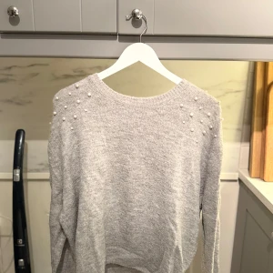 Ljusgrå stickad tröja med pärlor - Fin ljusgrå stickad tröja med pärldetaljer på axlarna som är från H&M.