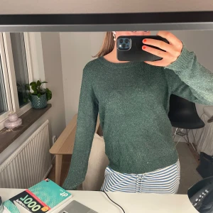 Mörkgrön stickad tröja från Vila - Mysig mörkgrön stickad tröja från Vila i storlek M. Tröjan har rund halsringning, ribbade muddar och lång ärm. Perfekt för lager-på-lager och chill dagar. Enkel och stilren design som funkar till det mesta.