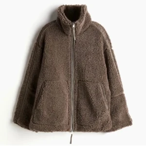 Brun teddyjacka med dragkedja - Mysig brun teddyjacka med hög krage och två stora fickor framtill. Jackan har en rak, loose passform och stängs med dragkedja. Perfekt för kyliga dagar när du vill vara både varm och snygg.