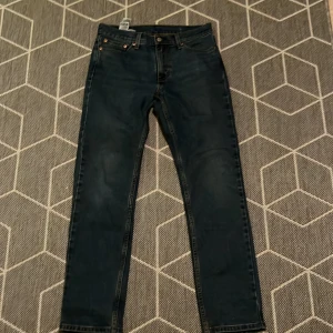 Levi's 511 mörkblå jeans 30/30 - Säljer ett par Levi's 511 jeans i mörkblå tvätt med klassisk femficksdesign och orangea sömmar. Jeansen har en slim passform och är tillverkade i slitstarkt denim. Perfekta för dig som gillar en tidlös och clean look.