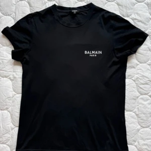 Svart Balmain Paris t-shirt i bomull - Svart t-shirt från Balmain Paris i mjuk bomull. Klassisk passform med rund hals och korta ärmar. Balmain är 100% äkta kvitto finns kom privat för de! Extremt lyxigt och bra kvalité på materialet!