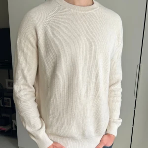 Beige stickad tröja från Zara - Säljer en stilren beige stickad tröja från Zara i storlek L. Tröjan har rund halsringning, ribbade muddar och är långärmad. Enkel och clean look som funkar året runt. Modellen är 190cm, 78kg. Skriv om ni har några som helst funderingar:)