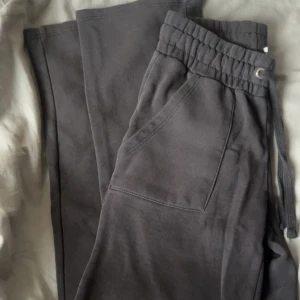 Mörkgrå mjukisbyxor XS med snörning - Mörkgrå mjukisbyxor i storlek XS med elastisk midja och snörning. Byxorna har praktiska sidfickor och är tillverkade i mjukt bomullsmaterial, perfekta för en chill och avslappnad stil.