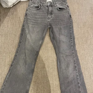 Grå bootcut jeans från Gina Tricot - Snygga grå jeans från Gina Tricot. De har bootcut-ben, klassisk femficksdesign och hög midja. Jeansen är tillverkade i ett mjukt denimtyg och har en stilren, tvättad grå färg som passar till det mesta.