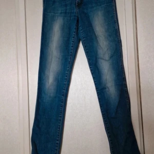 Blå jeans från Wrangler - Snygga blå jeans från Wrangler med klassisk tvätt och lätt slitning på låren. Modellen har raka ben och normal passform. Materialet är 97% bomull och 3% elastan för lite stretch och extra komfort. Perfekta för dig som gillar en tidlös jeanslook. Stretchen är tydlig på ett ställe (se bild). I övrigt har jag inte hittat några skavanker. Osäker på vad det innebär i europeiska storlekar men skulle tro det är en XS eller S. Stl W27 L34