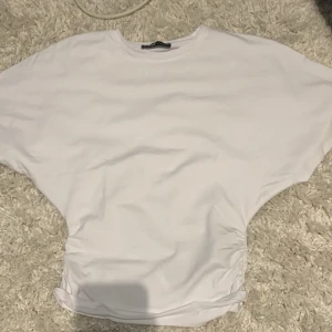 Vit loose topp från newyorker! - Säljer en vit topp från New yorker i storlek XXS. Modellen är loose fit med breda, korta ärmar och rund halsringning. Toppen har en enkel och clean look, perfekt till jeans eller kjol. Materialet känns mjukt och skönt mot huden. Priset kan diskuteras och om man vill ha fler bilder💗💐