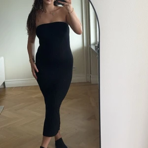 Svart axelbandslös långklänning - En svart, tight och axelbandslös långklänning med figursydd passform. 