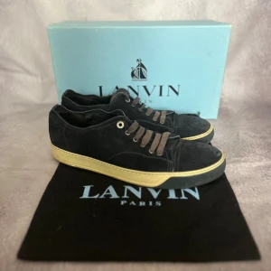Lanvin Mörkblåa Mocka Sneakers – EU 43 / UK 9 - ✨ Färg: Mörkblåa (Navyblue) mocka med kontrasterande beige mellansula och mörk yttersula 📏 Storlek: EU 43 / UK 9 📐 Innermått: ca 27,5 cm (normal passform för EU 43) ♻️ Skick: Okej begagnat skick (7/10) – välanvända, saknar innersula, tydliga tecken på användning 🧵 Material: Mocka (suede), gummisula, textilfoder