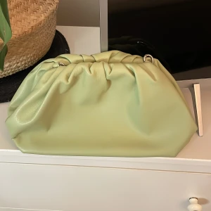 Ljusgrön clutch väska - Trendig ljusgrön clutch med mjuk, puffig form. Väskan är i hwlt nyskick, aldrig använt. Perfekt att bära i handen för en cool och sommrig outfit❣️❣️