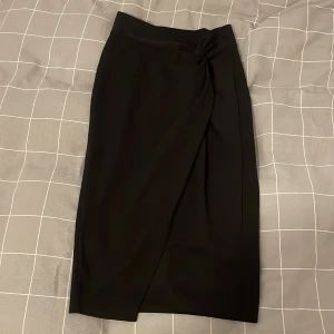 Svart omlottkjol - Snygg svart långkjol med omlott-design och twistdetalj i midjan.