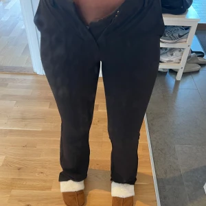 Svarta kostymbyxor med raka ben - Snygga svarta kostymbyxor med raka ben och klassiska fickor både fram och bak. Byxorna har bälteshällor och stängs med dragkedja och knapp. Perfekta för en clean och stilren look. Materialet känns mjukt och följsamt.