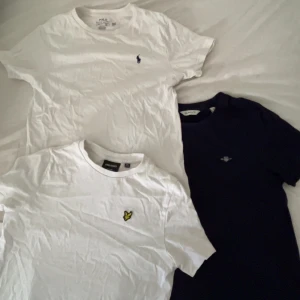 3-pack t-shirts Polo, Lyle & Scott, Gant - Tre snygga t-shirts: en vit från Polo Ralph Lauren med blå logga, en vit från Lyle & Scott med gul fågelmärke och en marinblå från Gant med broderad logga. Alla har rund hals och korta ärmar, tillverkade i mjuk bomull. Perfekt för dig som gillar klassiska märken. Köpt direkt från ralphlauren, lyle & scott och gant sidan. Cirka 1300 tillsammans för de 3. Tro inte att det kostar 1kr, kom privat för att diskutera pris. 
