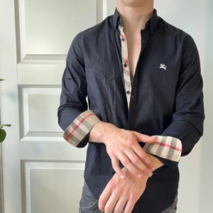 Burberry svart skjorta S - Burberry svart skjorta S, inga defekter! Sjukt najs och har det klassiska Burberry mönstret på många ställen. Modellen är 180,75 kg och passar honom perfekt 😊