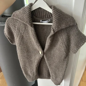 Kortärmad beige stickad kofta - Kortärmad stickad kofta i beige ton från Zara. Väldigt liten i storleken och aldrig använd!