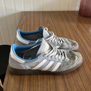 Adidas Spezial blå sneakers mocka - Säljer ett par Adidas Spezial sneakers i blå mocka med vita detaljer och klassiska tre ränder på sidorna. Skorna har blå insida, bruna gummisulor och snörning. Perfekta för dig som gillar retrostil och vill ha något unikt på fötterna.