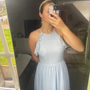 Ljusblå långklänning med volang - Superfin ljusblå långklänning med tunna axelband och volangdetaljer längs sidorna.🪽Klänningen har en flowy passform och är gjord i ett tunt, lätt material som ger en luftig känsla. Perfekt för sommarens alla tillfällen!✨🩵