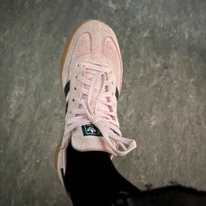 Adidas Samba rosa mocka sneakers - Säljer ett par Adidas Samba sneakers i ljusrosa mocka med klassiska mörkblå ränder. Skorna har snörning, gummisula i naturfärg och rund tå. Perfekt nyckfull hösten om man vill piffa upp sin outfit😍🤗Dem är använda 2-3 gånger och är i storlek 36 2/3 men passar nån som har storlek 37 med😇 