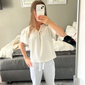 Vit blus med knyt från Kappahl - Supersöt vit blus från Kappahl i storlek 158/164. Den har korta ärmar, knytning vid halsen och är gjord i mjukt material 💗
