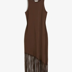Brun ärmlös klänning med fransar - Snygg brun ärmlös klänning med rund halsringning och långa fransar nertill som ger en cool och trendig look. Klänningen har en rak passform och är perfekt för dig som vill sticka ut med en unik detalj.