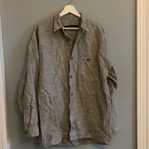 Vitsvart skjorta - Vitsvart rutig skjorta. Brunvitspräckliga knappar. Tjockt material. Storlek M. Gott skick, inga defekter eller missfärgningar.