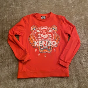Orange Kenzo sweatshirt med tigertryck - Cool Orange sweatshirt från Kenzo med det ikoniska broderade tigerhuvudet och texten 'KENZO PARIS' på bröstet.