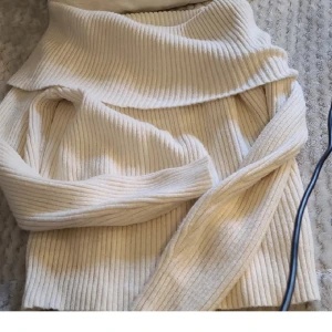 Ribbad offshoulder tröja i beige - Säljer en ribbad offshoulder tröja i beige med lång ärm. Tröjan har en bred krage som vilar över axlarna och är tillverkad i ett mjukt stickat material. Perfekt för dig som gillar en stilren och trendig look.