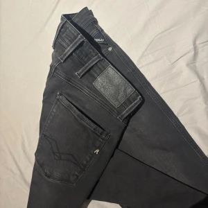 Svarta Replay jeans slim fit - Svarta jeans från Replay med klassisk femficksdesign och raka ben. Snygga detaljer som Replay-logga på fickan och svart läderpatch bak. Jeansen har normal passform och är tillverkade i mjukt denimtyg som sitter skönt hela dagen. Storlek 29/32