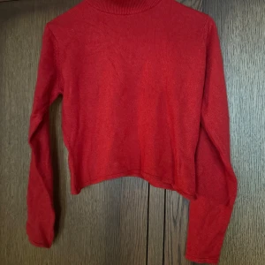 Röd polotröja från Jois & Jo - Snygg röd polotröja från Jois & Jo i mjukt stickat material. Tröjan har lång ärm, croppad passform och en klassisk polokrage. Perfekt för dig som gillar enkel stil med lite edge. Passar dig som vill ha en färgklick i garderoben.