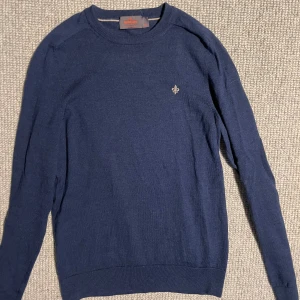 Mörkblå merinoullströja från Morris XS - Säljer en stilren mörkblå stickad tröja från Morris i 100% merinoull. Tröjan har rund halsringning, ribbade muddar och en liten broderad logga på bröstet. Perfekt för dig som gillar klassisk och enkel stil. Pris kan diskuteras.