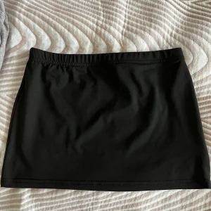 Svart lowwaist minikjol  - Enkel och stilren svart minikjol i stretchigt material. Kjolen har rak passform och resår i midjan för extra komfort. Perfekt att matcha med en crop top eller oversized hoodie.