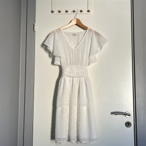 Vit prickig klänning från Dry Lake - Superfin vit klänning från Dry Lake med prickigt mönster, v-ringning och volangärmar. Klänningen har markerad midja med knytband bak och är tillverkad i ett lätt, luftigt material. Den är i storlek S, men skulle säga Xs. Perfekt för sommarens alla tillfällen!