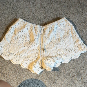 Vita spets-shorts  - Superfina vita shorts från Double11.11 i spets med blommigt mönster och snygg snörning i midjan. De har elastisk midja och vågig kant nertill för en extra söt look.  Är storlek M/L men skulle säga att dom passar S/M