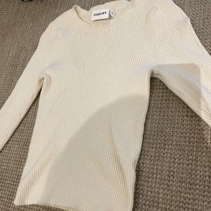 Ribbad beige tröja från Kappahl XS - Säljer en ribbad beige långärmad tröja från Kappahl i storlek XS. Tröjan har en snygg rund hals och är figurnära i modellen. Perfekt att styla med jeans eller kjol för en clean look. Materialet är mjukt och stretchigt, vilket gör den skön att bära.