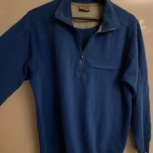 Blå half zip tröja från Clique XS - Mörkblå långärmad tröja från Clique i storlek XS. Tröjan har en praktisk half zip-dragkedja framtill och en liten bröstficka. Tillverkad i mjuk bomull, perfekt för kyligare dagar.