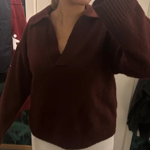 Vinröd stickad tröja  - Mysig vinröd stickad tröja med v-ringning och bred krage. Lite nopprig men det går lätt att fixa. 