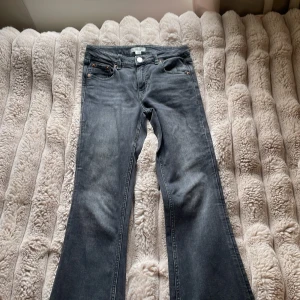 Mörkgrå bootcut jeans - Snygga mörkgrå jeans med bootcut passform och klassisk femficksdesign. Jeansen har en lätt tvättad look och råa kanter nertill för en cool vibe. Perfekta för dig som gillar en avslappnad men trendig stil.
