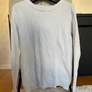 Vit stickad tröja med rund hals - En enkel och perfekt vit stickad tröja med rund halsringning och långa ärmar. Tröjan har ribbade muddar vid ärmslut och nederkant! Är nästan säker på storleken, men kan kolla om någon är intresserad!