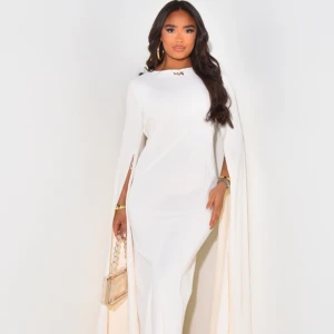 Vit långklänning med capeärmar - Supersnygg vit långklänning med capeärmar och figurnära passform. Klänningen har rund halsringning och långa, dramatiska ärmar som ger en cool och elegant look. Perfekt för dig som vill sticka ut och känna dig extra glam.