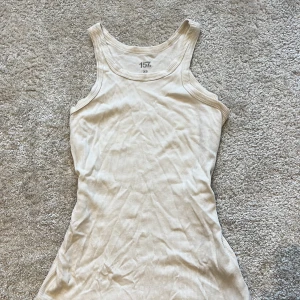 Beige ribbad linnetopp från 157 - Säljer en beige ribbad linnetopp från 157 i storlek XS. Toppen är ärmlös med klassisk rund halsringning och har en slim passform. Perfekt att styla med jeans eller shorts för en enkel och clean look. Kontakta för fler bilder 🩷