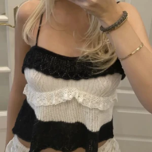 Zara stickad linnetopp med volanger - Supersöt stickad linnetopp med svarta och vita ränder. Toppen har smala axelband och volangdetaljer på bröstet och längs ränderna. Perfekt för dig som gillar en lekfull och trendig stil med en touch av retro.