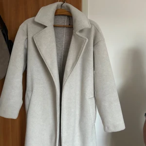 Vit/Beige långkappa - Kappa använd endast en gång. Extremt bra skick, finns inga skador eller defekter. Köpt från Amisu för 500kr💗 Storlek Xs men passar jätte fint för mig som har storlek S.