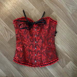 Röd korsett med svarta snörningar - Säljer en röd korsett med svarta snörningar som tyvärr var för liten för mig. Aldrig använd. Perfekt nu till halloween🥰