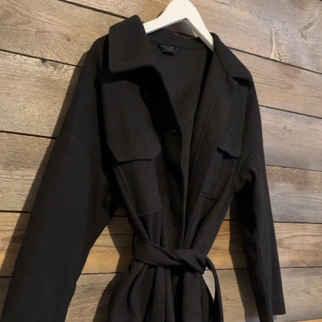 Svart kappa med bälte och stora fickor