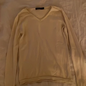 Beige v-ringad tröja London Fog - Beige v-ringad tröja från London Fog i storlek S. Tröjan har lång ärm och är tillverkad i ett mjukt stickat material som känns skönt mot huden. Enkel och stilren design som funkar till många olika looks. Perfekt för dig som gillar neutrala färger. Tröjan har en fläck på högra sidan, fast skall försöka fixa bort den!!!
