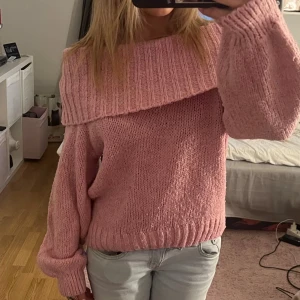 Rosa offshoulder stickad tröja - Superfin rosa stickad tröja med bred ribbad krage som sitter offshoulder. Tröjan har lång ärm och en loose fit, perfekt för dig som gillar en avslappnad men ändå söt stil. Passar perfekt till jeans eller kjol för en trendig look💕
