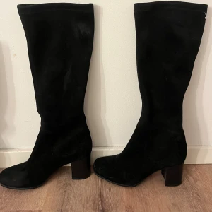 Svarta stövlar med klack - Snygga svarta stövlar med rund tå och stabil klack. Stövlarna har en klassisk siluett som går upp till knäet och passar perfekt till både jeans och kjol. Materialet är mocka och färgen är helsvart. står ingen storlek på dom men passar mig som har 38/39.  nypris 1999:- pris kan diskuteras
