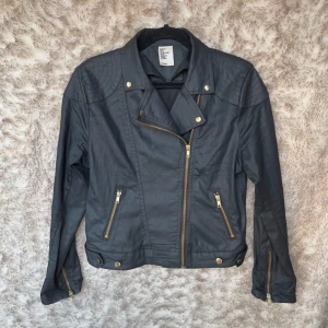 Svart bikerjacka från H&M &Denim - Snygg svart bikerjacka från H&M &Denim i storlek 38. Materialet är syntet med en matt finish. 