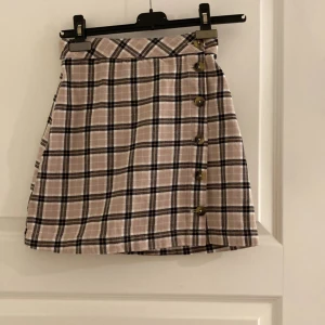 Jättefin kjol från hm  - Storlek 32 men motsvarar stl 34. Beige och rutig med knappar. Kjolen är i fint skick! 