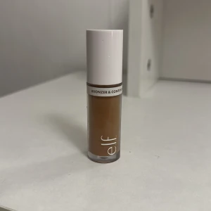 e.l.f. Camo Liquid Bronzer & Contour - Flytande bronzer och contour från e.l.f. i en smidig tub med vit kork. Färgen är en varm brun nyans som passar perfekt för att skapa markerade kindben och en solkysst look. Enkel att applicera och blenda för ett naturligt resultat. Använd 2-3 gånger.