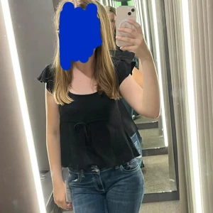 Svart blus med volangärm och knyt - Svart blus med volangärmar och knyt i midjan. 